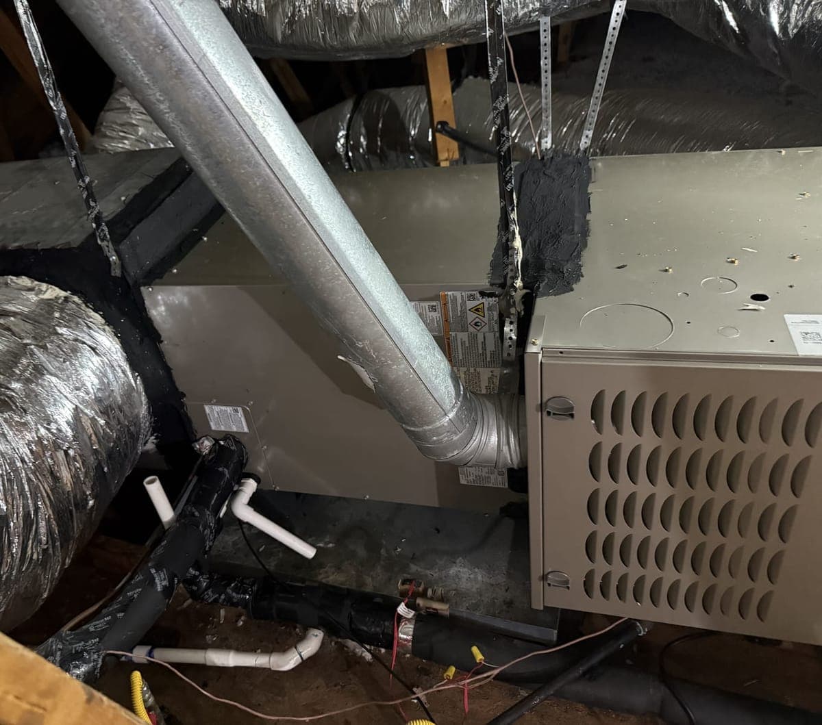 Close view of a new Carrier indoor unit with its duct, drain, and vent pipe connections